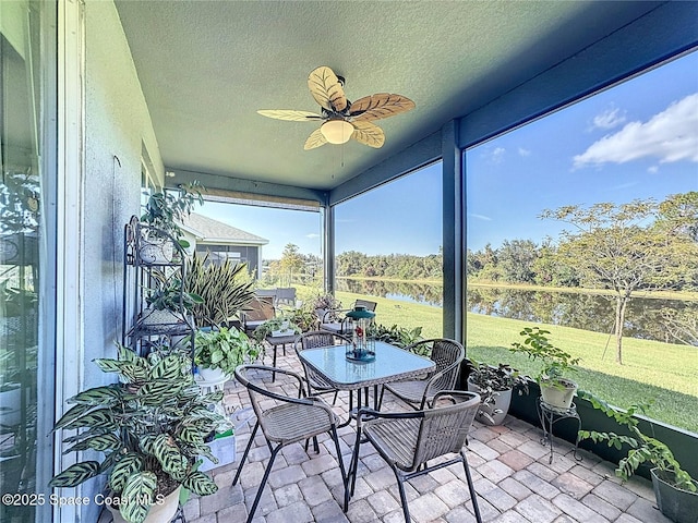 sunroom featuring a water view and a ceiling fan