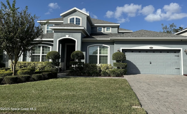 view of front of property with a front lawn, decorative driveway, a garage, and stucco siding