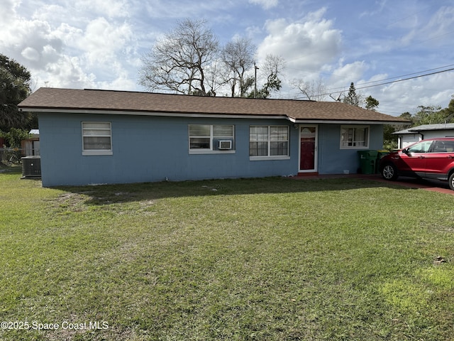 single story home featuring roof with shingles, concrete block siding, central AC, and a front lawn