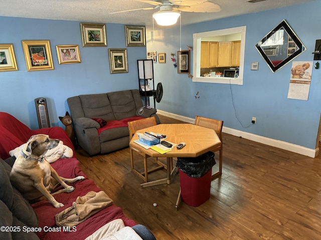 living room with visible vents, baseboards, wood finished floors, a textured ceiling, and a ceiling fan