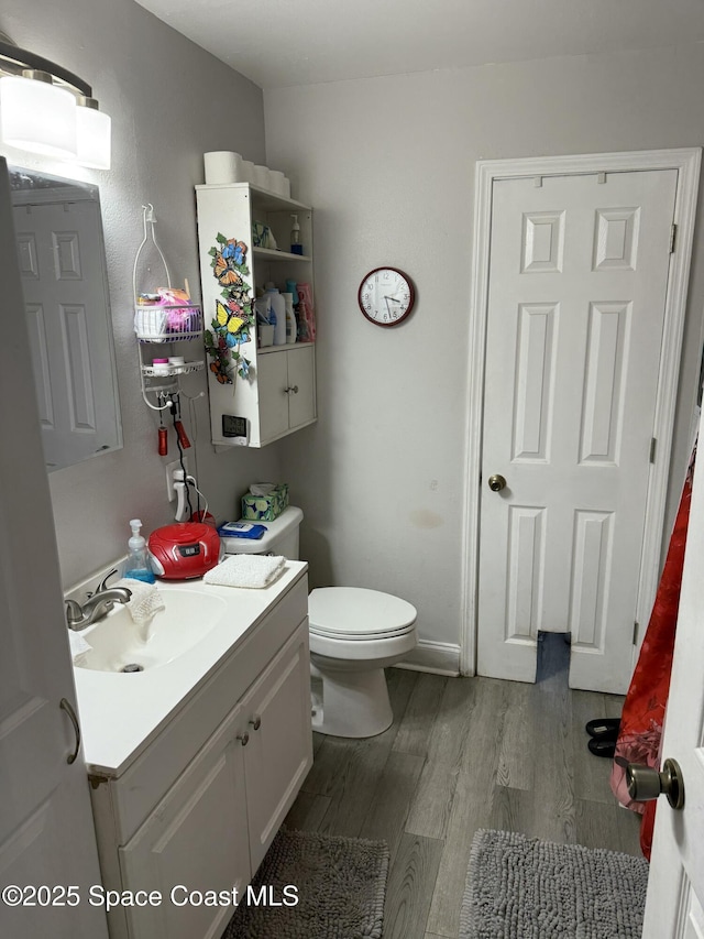 half bath featuring toilet, wood finished floors, and vanity