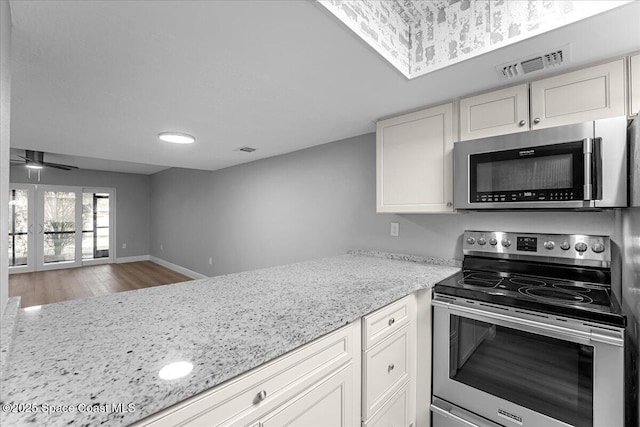 kitchen featuring visible vents, appliances with stainless steel finishes, wood finished floors, and light stone countertops