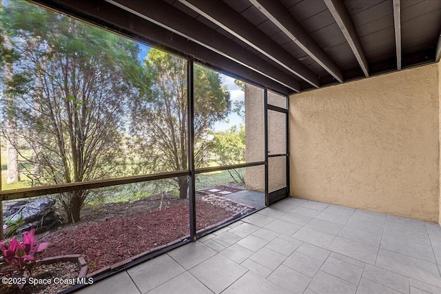 unfurnished sunroom featuring beam ceiling