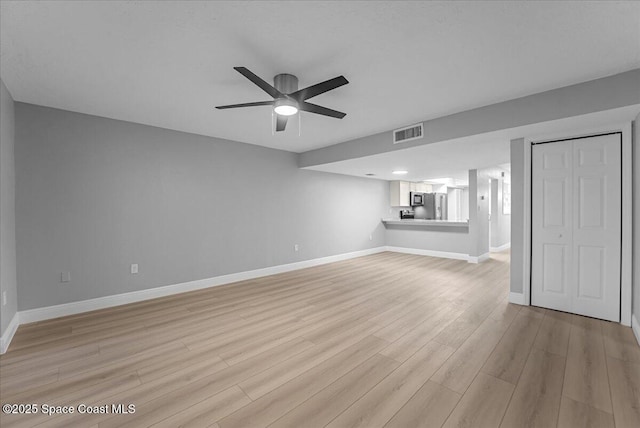 unfurnished living room with visible vents, light wood-style flooring, a ceiling fan, and baseboards