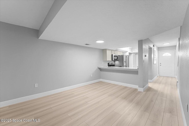 unfurnished living room featuring visible vents, baseboards, and light wood-style floors