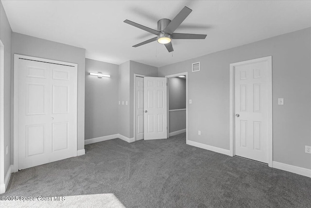 unfurnished bedroom with visible vents, two closets, carpet floors, baseboards, and ceiling fan