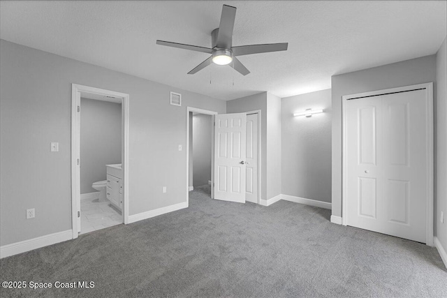 unfurnished bedroom with visible vents, multiple closets, ensuite bathroom, carpet flooring, and baseboards