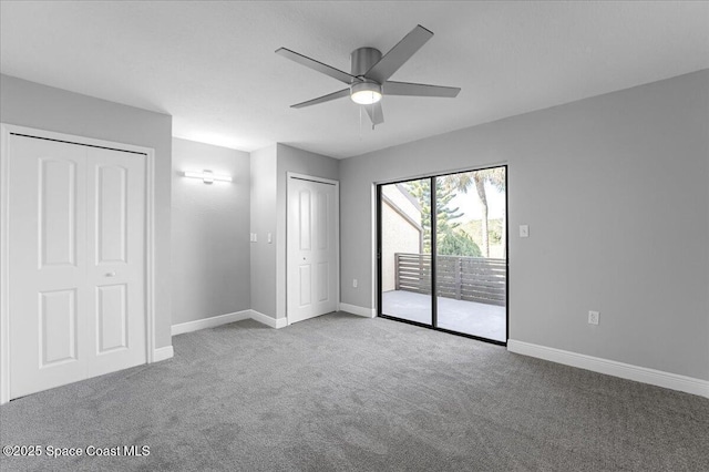 unfurnished bedroom with baseboards, carpet, multiple closets, and access to outside