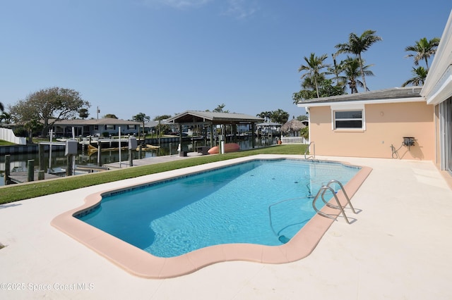 pool with a water view, a yard, a patio area, boat lift, and a boat dock