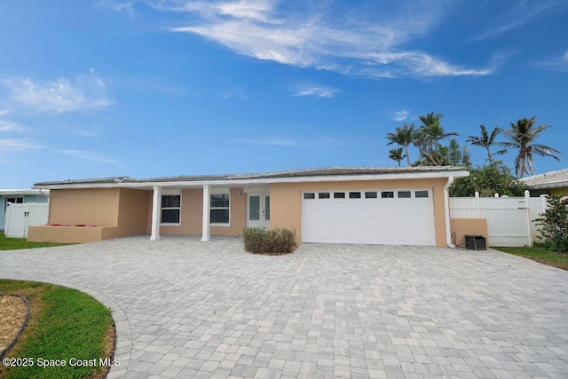 single story home with decorative driveway, fence, an attached garage, and stucco siding