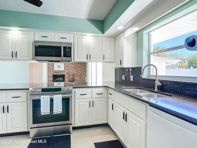 kitchen featuring a sink, stainless steel appliances, a textured ceiling, white cabinetry, and tasteful backsplash