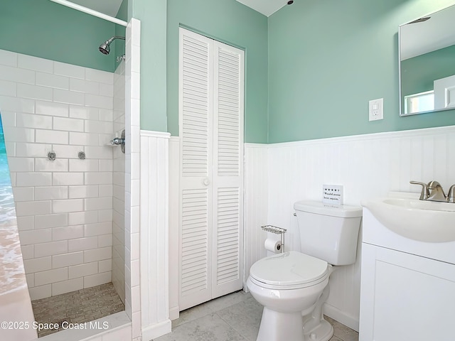 bathroom with a shower stall, toilet, a closet, and wainscoting