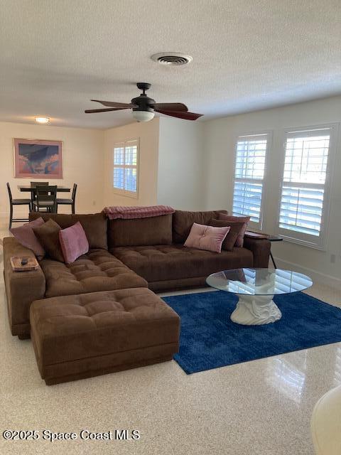 living room featuring visible vents, a textured ceiling, and speckled floor