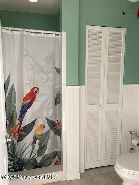 bathroom featuring tile patterned floors, a wainscoted wall, curtained shower, and toilet