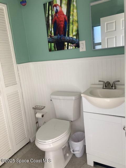 bathroom featuring tile patterned floors, vanity, toilet, and wainscoting