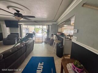 living area with ceiling fan and crown molding