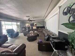 living room featuring ceiling fan, carpet, and a textured ceiling