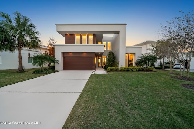 contemporary home featuring a yard, a garage, driveway, and stucco siding