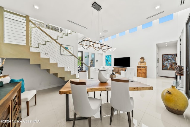 dining space featuring stairway, light tile patterned floors, baseboards, and a towering ceiling