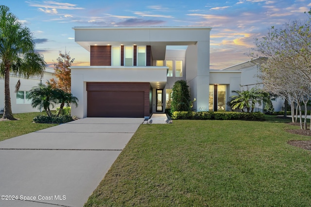 modern home featuring concrete driveway, a garage, a front yard, and stucco siding