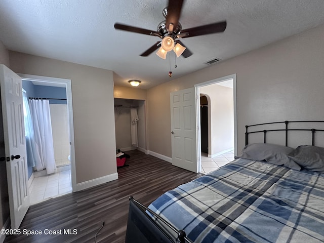 bedroom featuring wood finished floors, baseboards, visible vents, arched walkways, and a textured ceiling