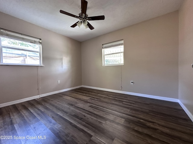 spare room with a ceiling fan, dark wood-type flooring, and baseboards