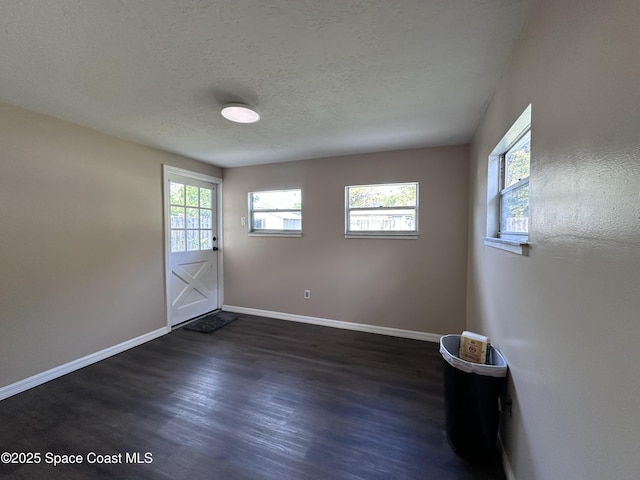 interior space with dark wood-style floors, a textured ceiling, and baseboards