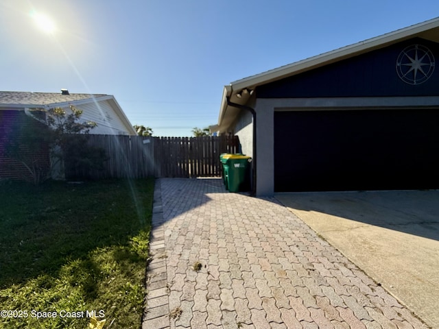 view of home's exterior featuring driveway, a garage, and fence