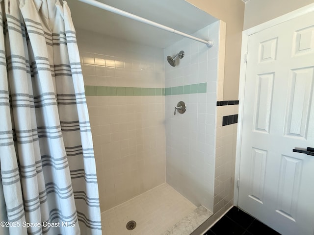 full bathroom featuring a tile shower and tile patterned flooring