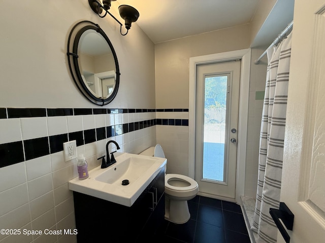 full bath featuring vanity, tile patterned flooring, wainscoting, tile walls, and toilet