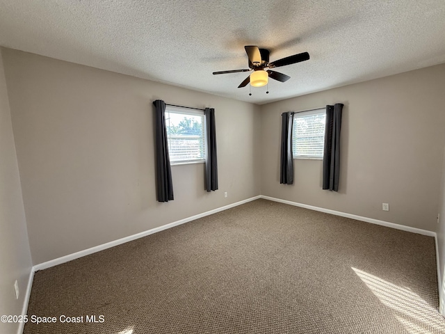 empty room with ceiling fan, a textured ceiling, baseboards, and carpet floors