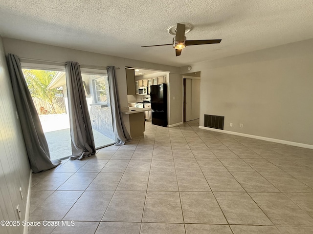 spare room featuring visible vents, baseboards, light tile patterned floors, a textured ceiling, and a ceiling fan