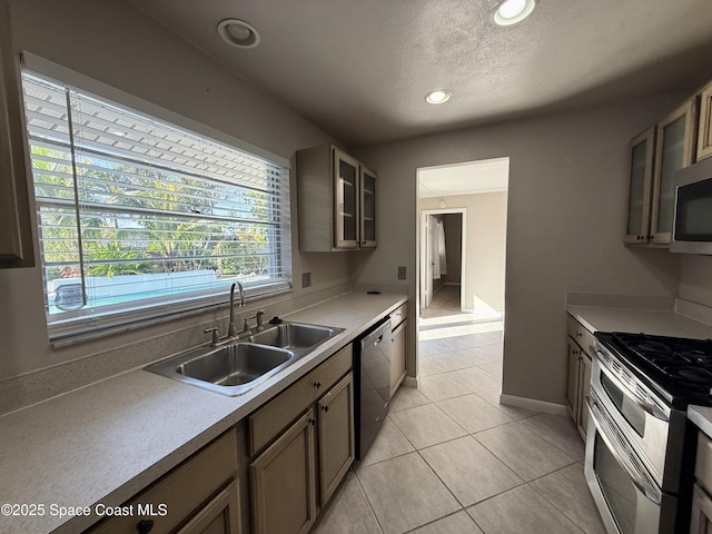 kitchen with glass insert cabinets, light countertops, recessed lighting, stainless steel appliances, and a sink