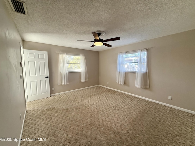 carpeted empty room featuring visible vents, a textured ceiling, a ceiling fan, and baseboards