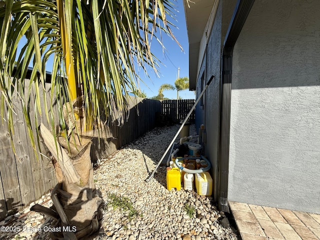 view of side of home featuring a fenced backyard and stucco siding