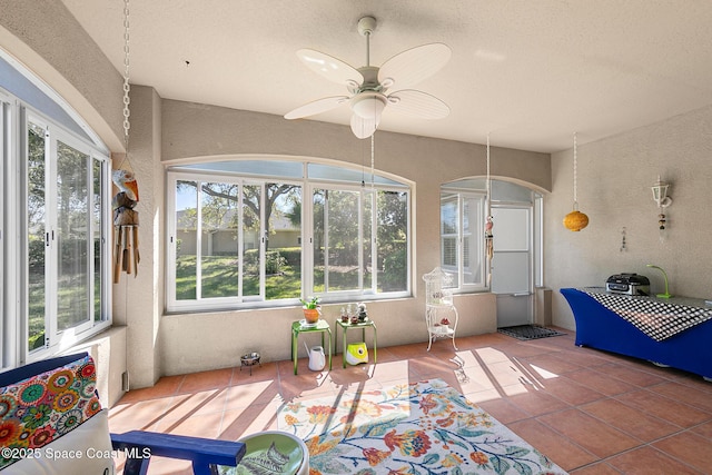 sunroom / solarium featuring arched walkways and a ceiling fan