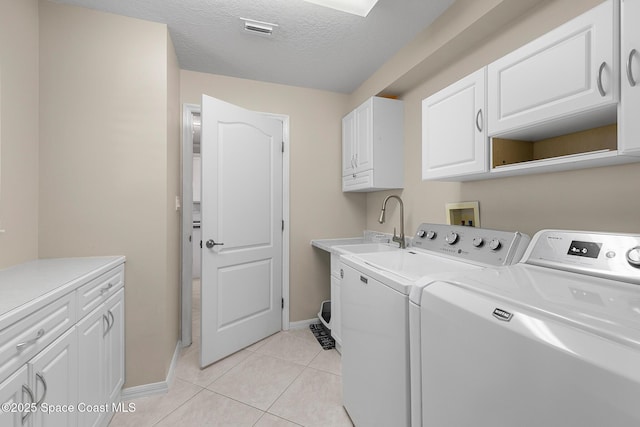 laundry room with washing machine and clothes dryer, visible vents, light tile patterned floors, cabinet space, and a textured ceiling