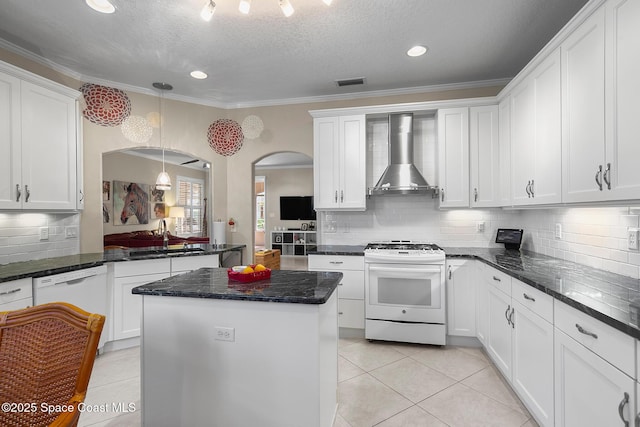 kitchen with visible vents, a sink, white appliances, arched walkways, and wall chimney range hood