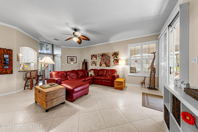 living room with a ceiling fan, baseboards, light tile patterned flooring, a textured ceiling, and crown molding