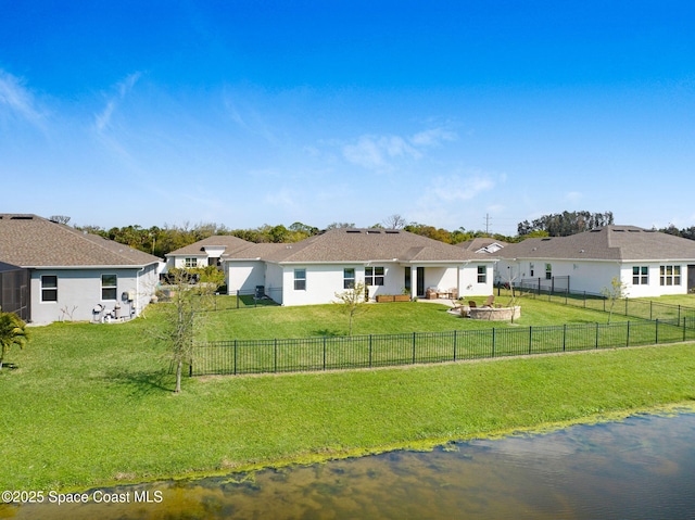 view of front of home with a front lawn, a fenced backyard, a water view, and a patio area