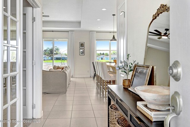 corridor with light tile patterned floors, baseboards, a healthy amount of sunlight, and recessed lighting