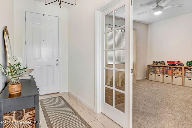 entryway featuring light tile patterned floors, baseboards, light carpet, and a ceiling fan