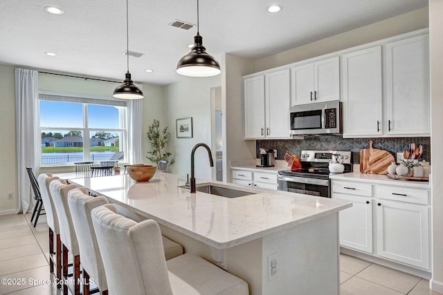 kitchen with light tile patterned floors, visible vents, a sink, stainless steel appliances, and backsplash