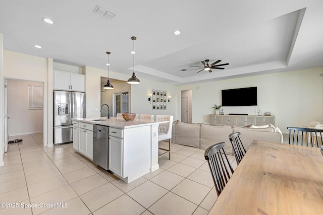 kitchen featuring light tile patterned floors, visible vents, stainless steel appliances, and a tray ceiling