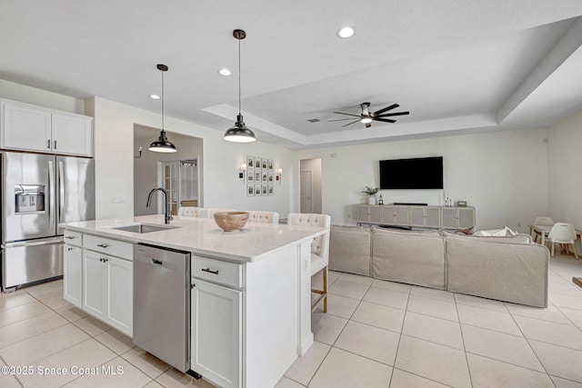 kitchen featuring a sink, a raised ceiling, appliances with stainless steel finishes, and light tile patterned floors