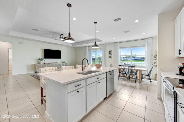 kitchen with range with electric cooktop, a sink, a tray ceiling, a breakfast bar area, and dishwasher
