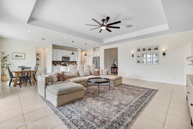 living area featuring a tray ceiling, light tile patterned flooring, and visible vents