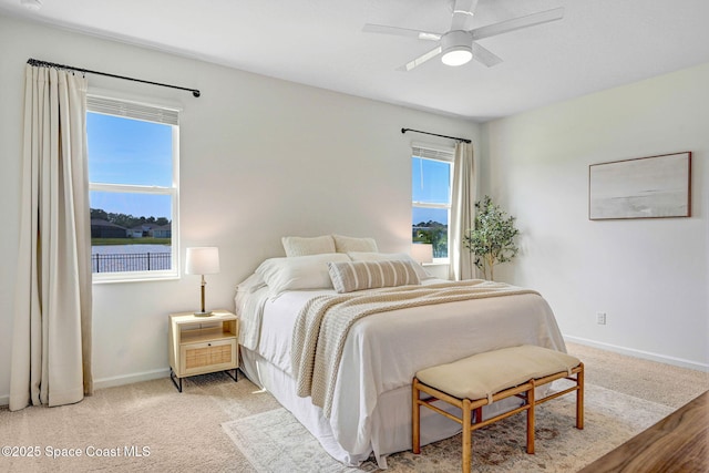 bedroom with light carpet, a ceiling fan, and baseboards