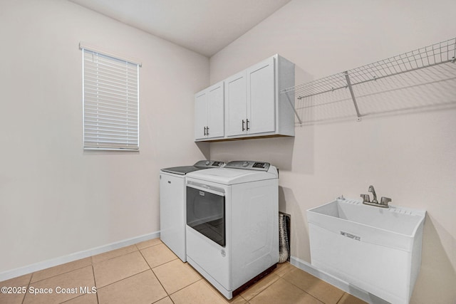laundry area with baseboards, washing machine and dryer, light tile patterned floors, cabinet space, and a sink