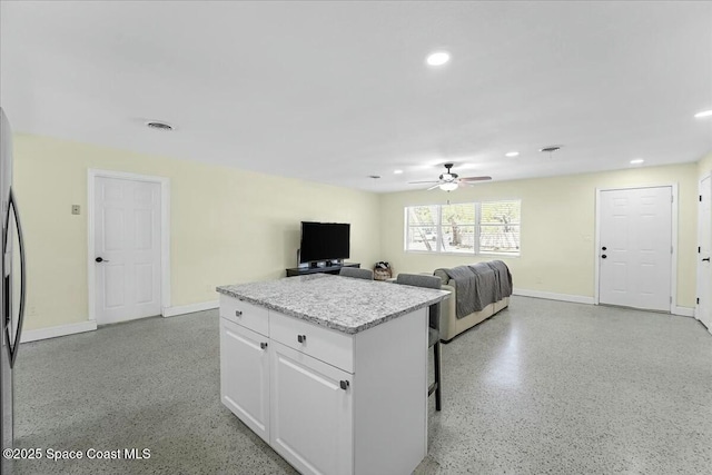 kitchen featuring a ceiling fan, a kitchen island, recessed lighting, white cabinets, and light speckled floor